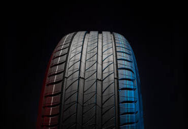 New car tire. Road wheel on dark background. Summer Tire with asymmetric tread design. Driving car concept.